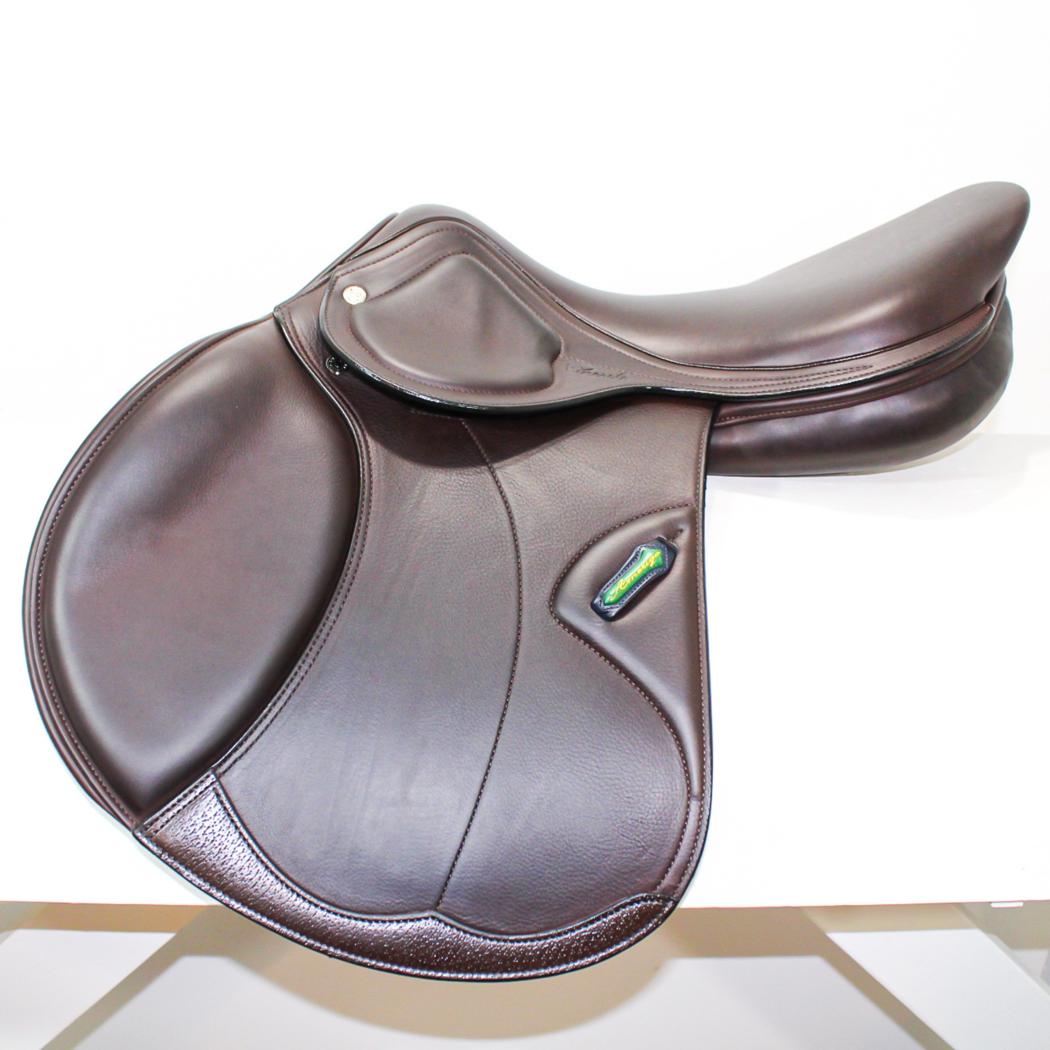 Left side profile view of an Amerigo dual flap jump saddle in dark brown calf leather, with a green and yellow Amerigo logo loop.