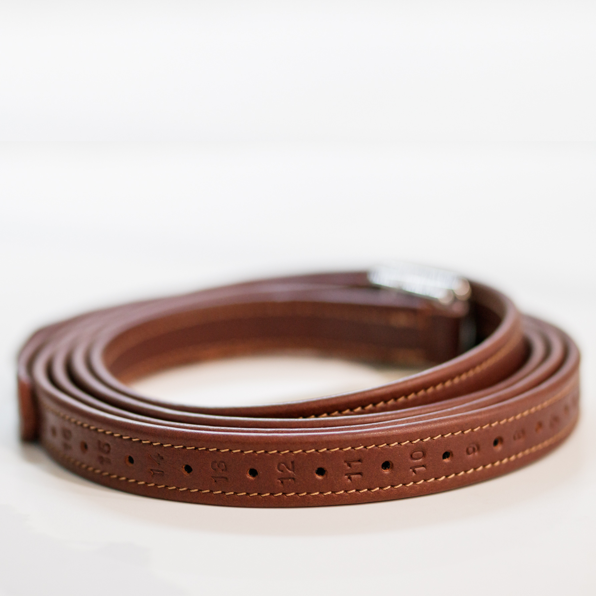 A rolled-up brown Meyer stirrup leather, featuring numbered holes and complimentary stitching.