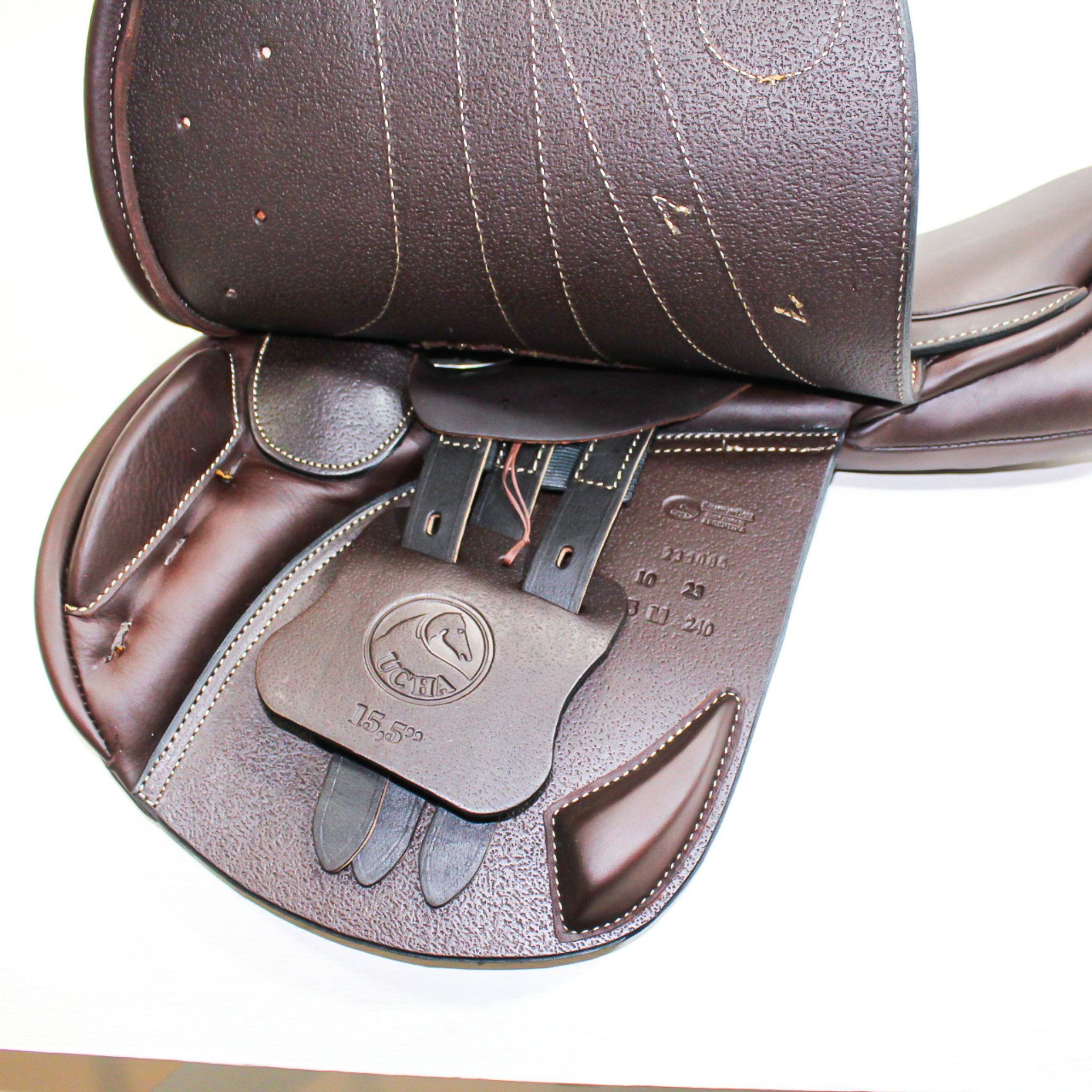Left side profile view of an Ucha Joven dual flap jump saddle with the main flap lifted to see the billets, front blocks, and back blocks.