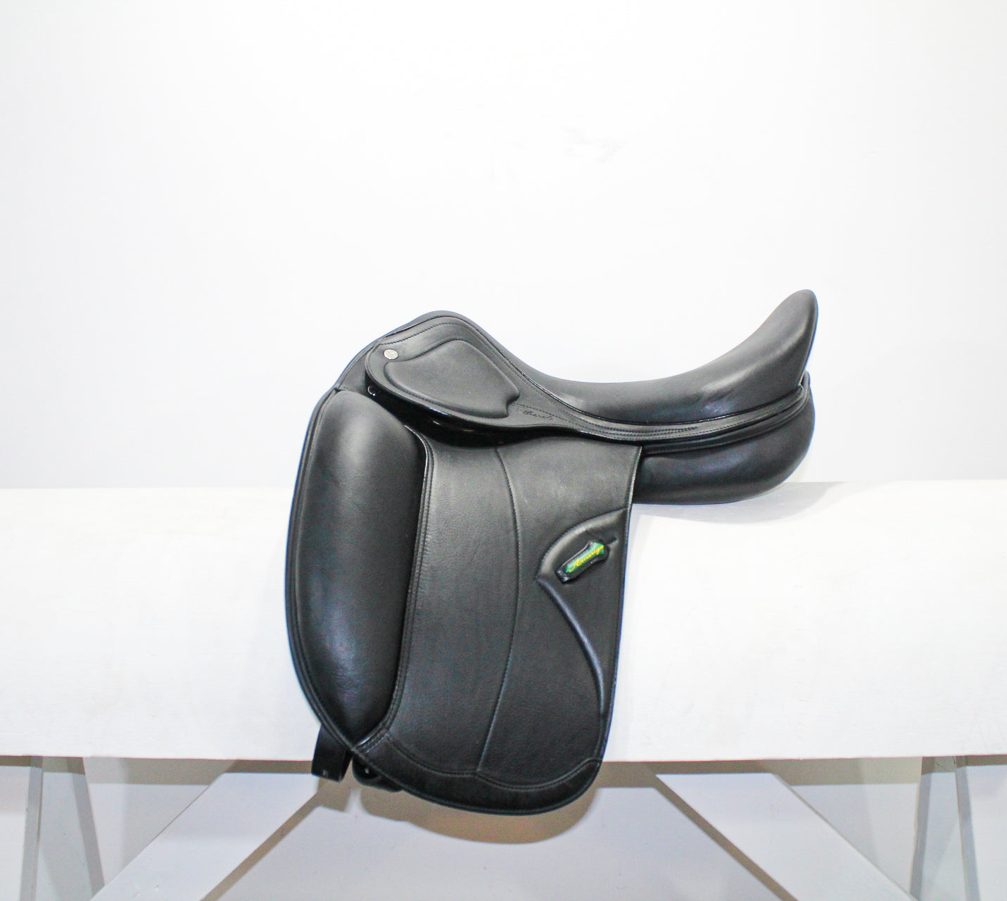 Left side profile view of an Amerigo Pasubio dressage saddle in black calf leather, with a green and yellow Amerigo logo loop.