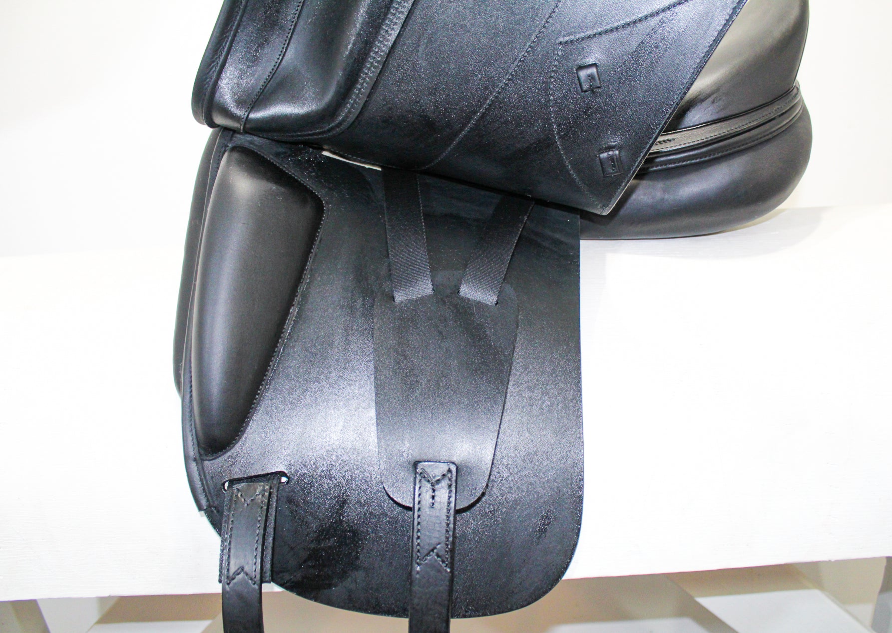 Left side profile view of an Amerigo Pasubio dressage saddle with the main flap lifted to see the billets and front blocks.