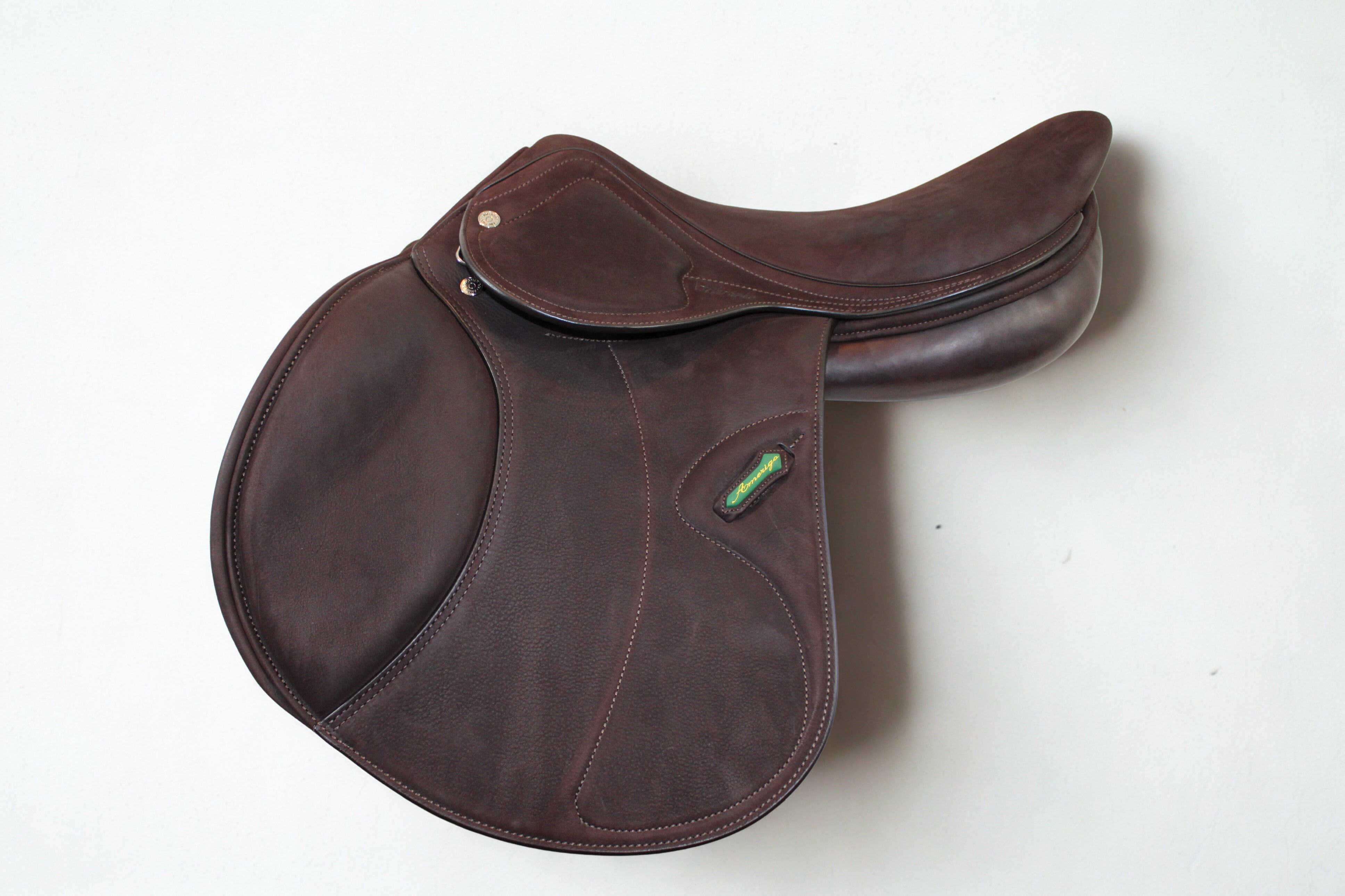 Left side profile view of an Amerigo DJ dual flap jump saddle in brown buffalo leather, with a green and yellow Amerigo logo loop.