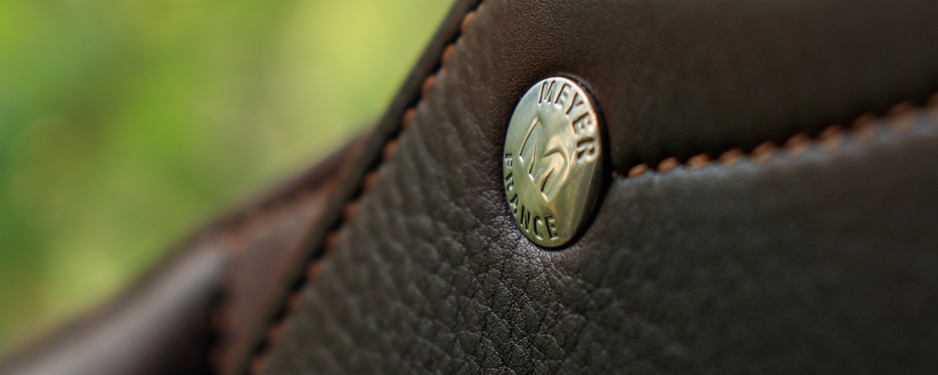 Close up of a brown Meyer jump saddle with a pin engraved "Meyer France".