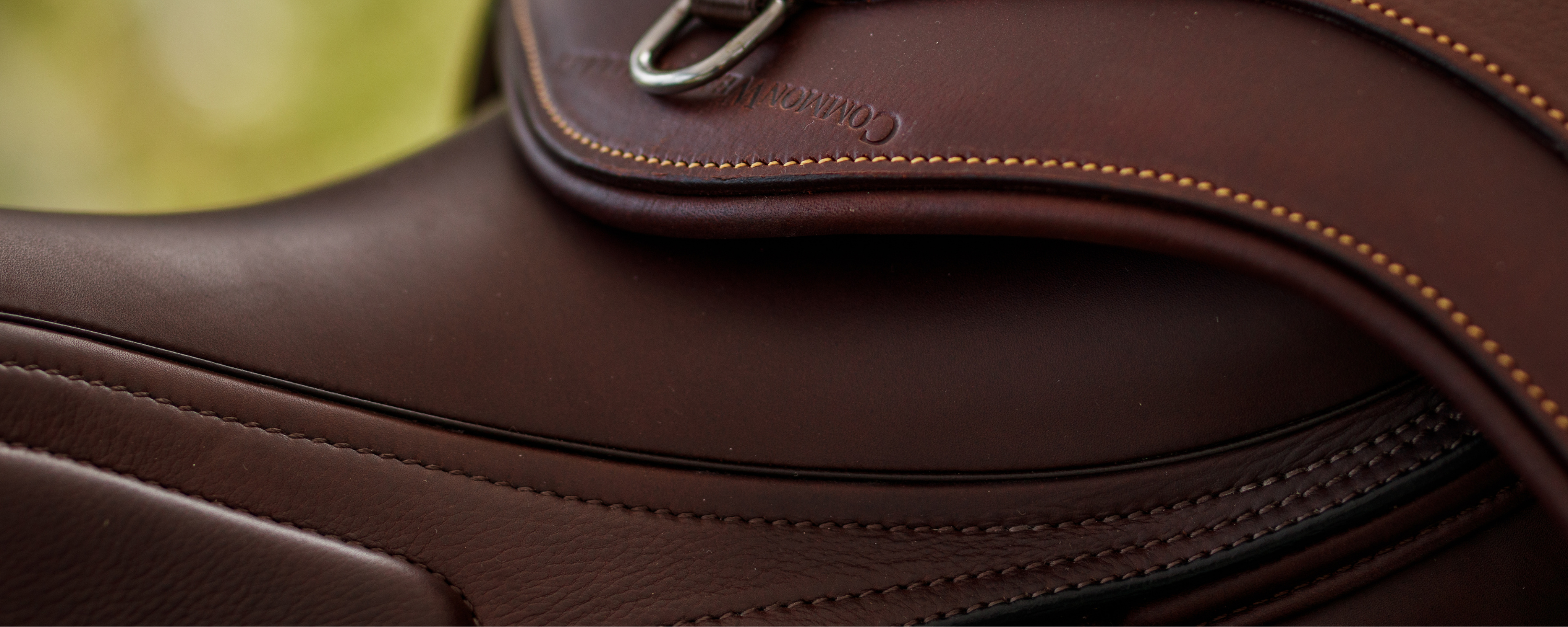 Close-up of a dark brown leather Amerigo Vesuvio saddle with an anatomical girth draped over it.