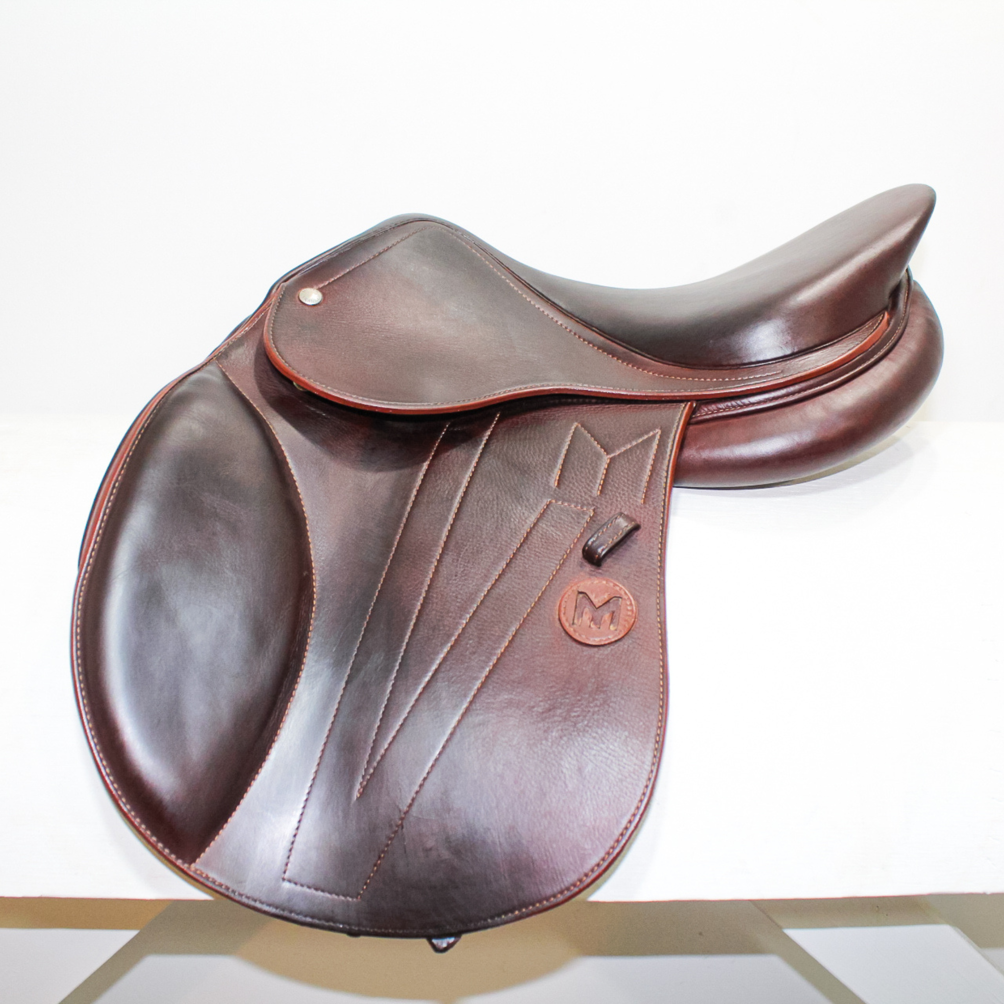 Left side profile view of a Meyer Kids Act 1 dual flap jump saddle in brown calf leather, with a leather Meyer logo on the flap