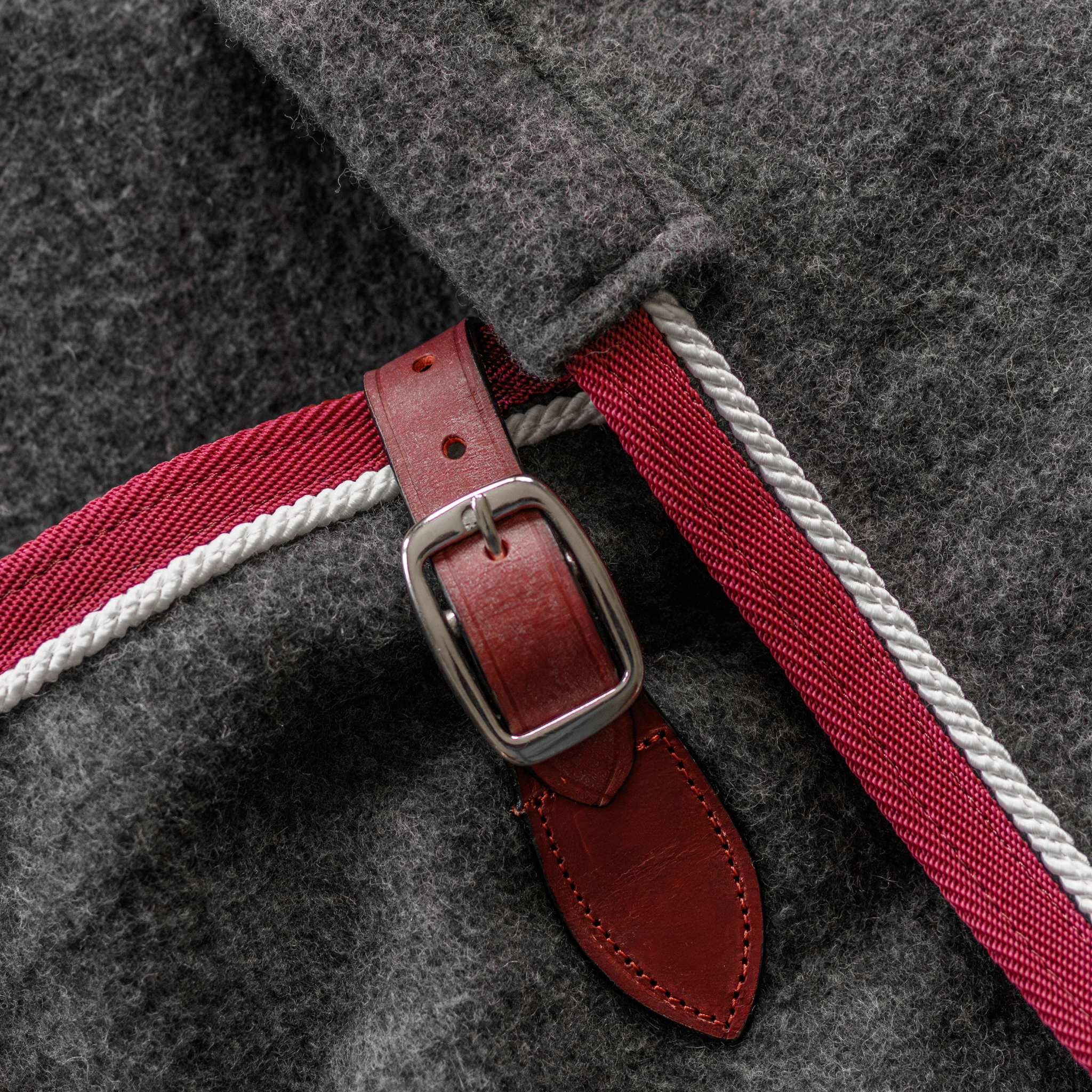 Close-up of a grey polyester show sheet with burgundy binding, grey cord, and leather chest strap.