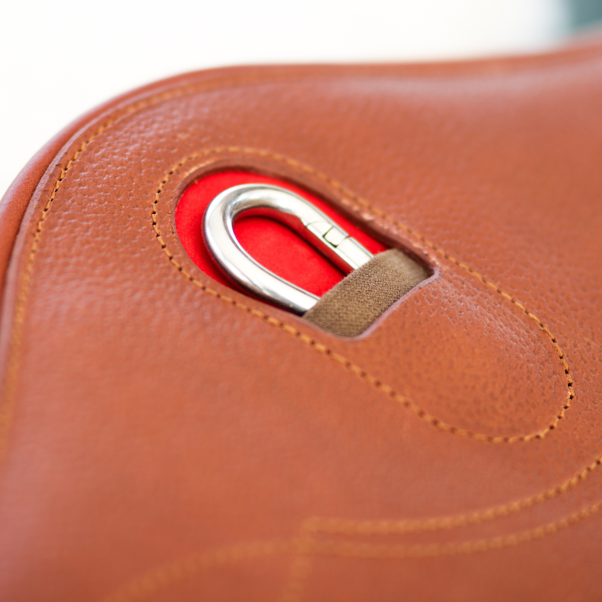 A brown Meyer stud girth with a durable belly pad, centre carabiner with red accent, and fancy stitch design