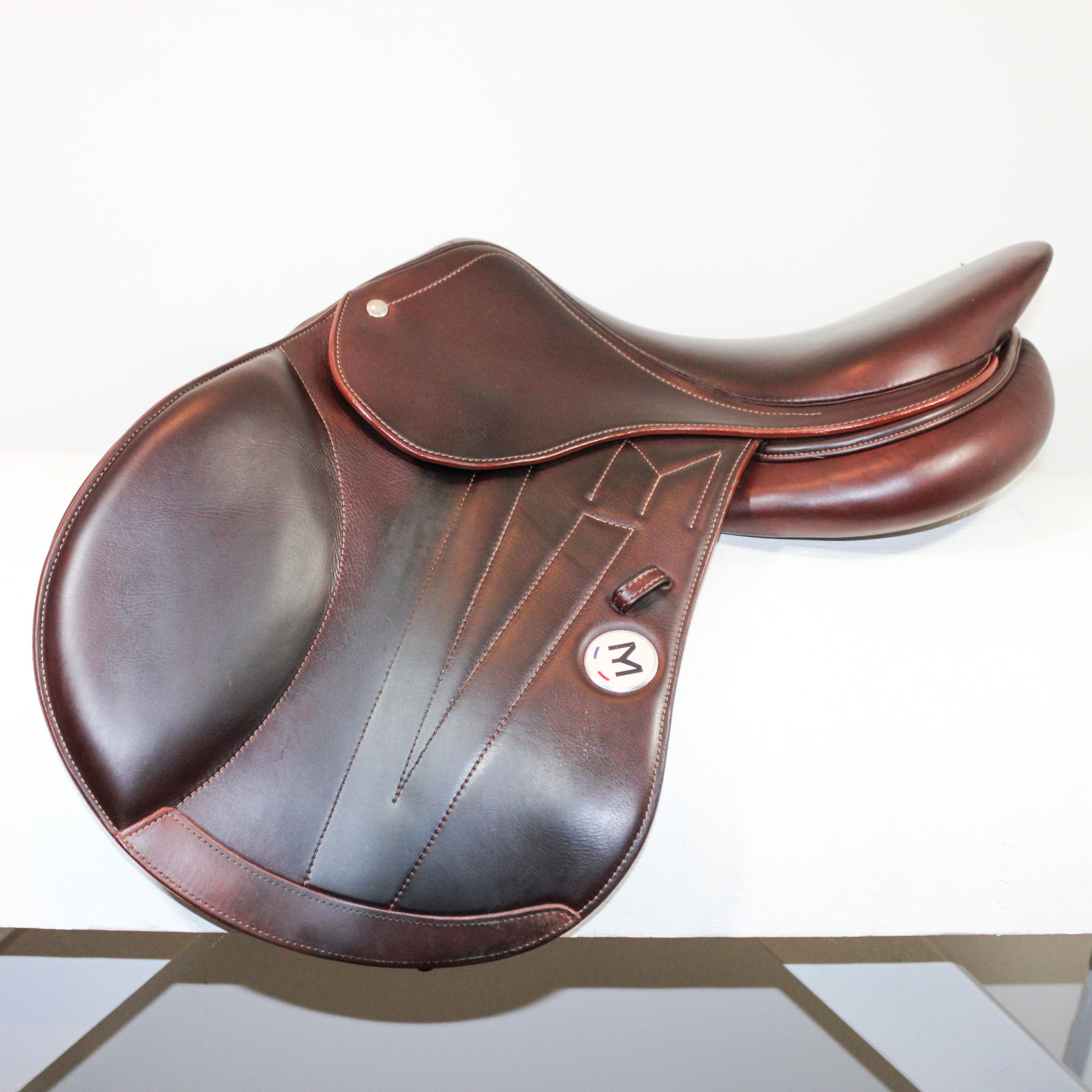 Left side profile view of a Meyer Act 2 jump saddle in brown calf leather with a white Meyer logo, decorative stitching on flap, and lower flap reinforcement.