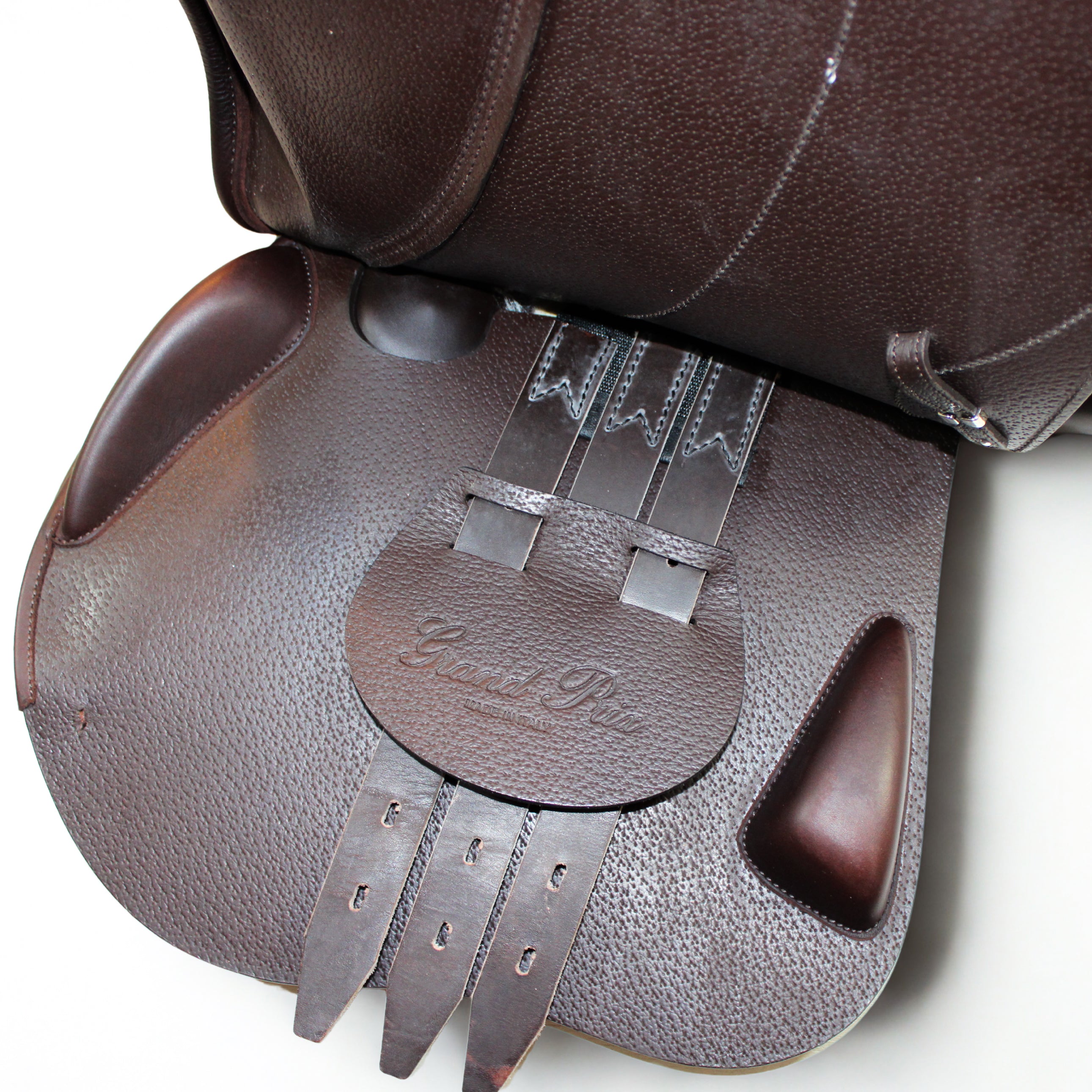 Left side profile view of an Equipe Grand Prix dual flap jump saddle with the main flap lifted to see the billets, front blocks, and back blocks. The underside of the main flap and the sweat flap have a grain texture.