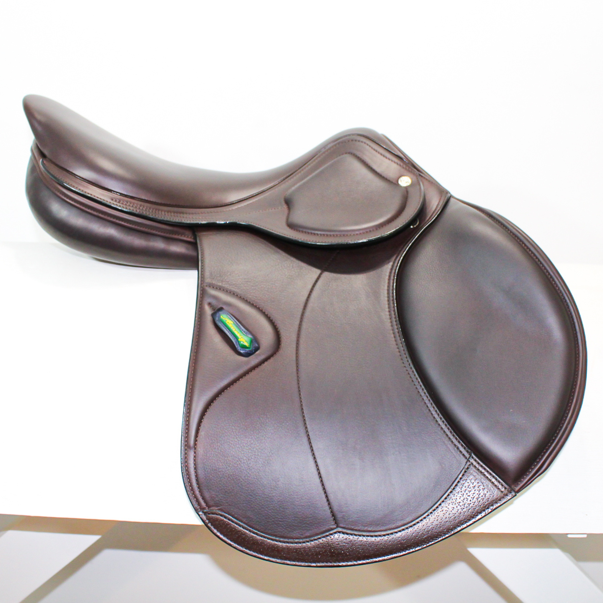 Left side profile view of an Amerigo dual flap jump saddle in dark brown calf leather, with a green and yellow Amerigo logo loop.