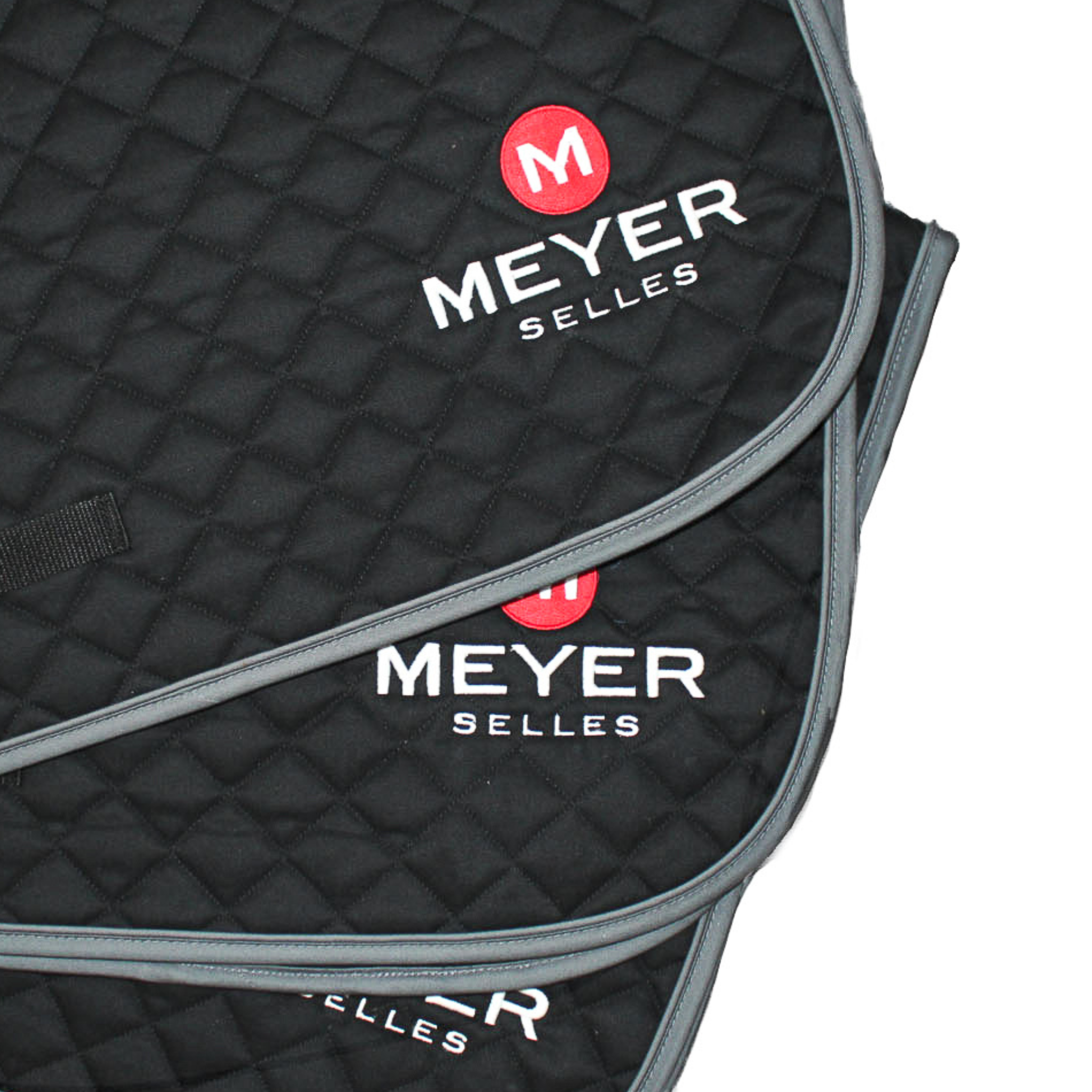 Multiple black quilted Ogilvy saddle pads stacked on top of eachother, showing the Meyer logo.