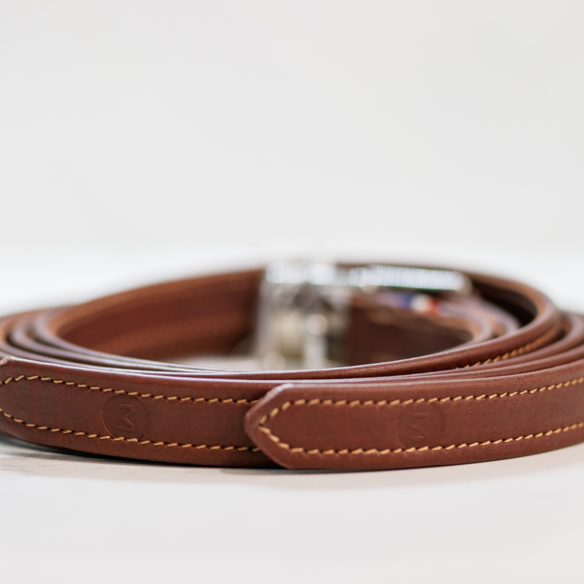 A rolled-up brown Meyer stirrup leather, featuring numbered holes and complimentary stitching.