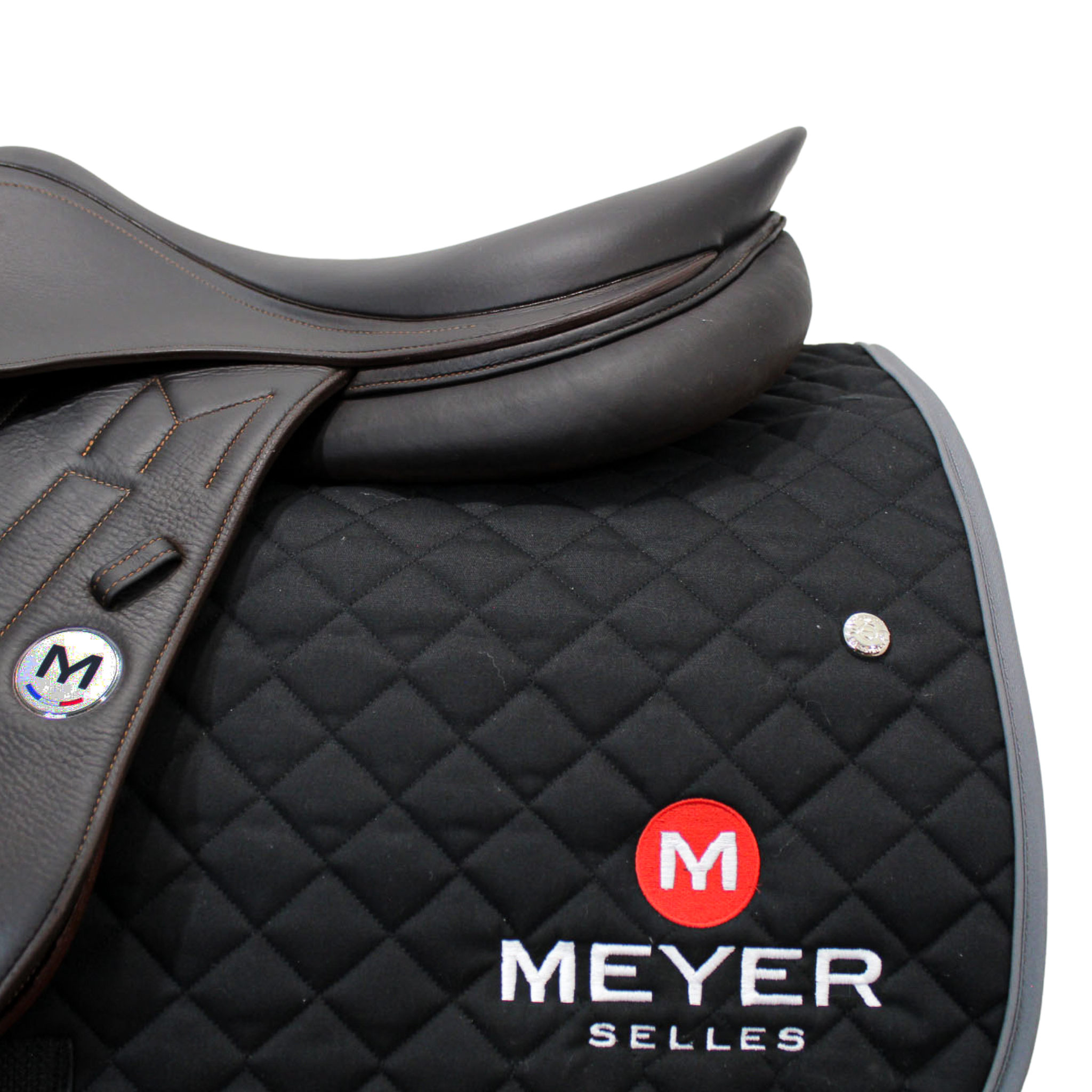 A black quilted Ogilvy saddle pad with a Meyer logo embroidered on the back left corner of the pad, underneath a Meyer saddle.