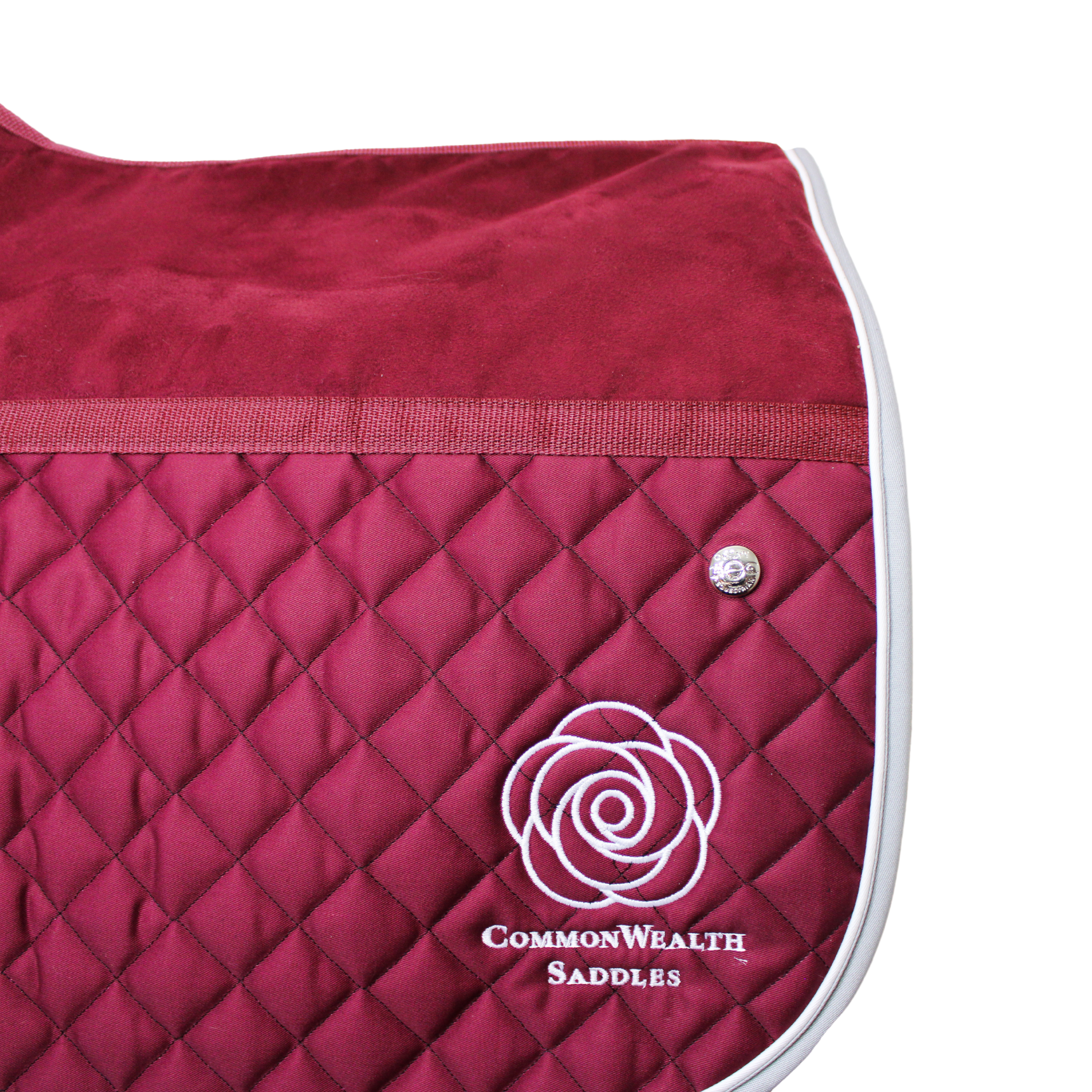 A burgundy friction-free Ogilvy saddle pad with a microfibre upper and quilted lower, and a CommonWealth logo embroidered on the back left corner of the pad.