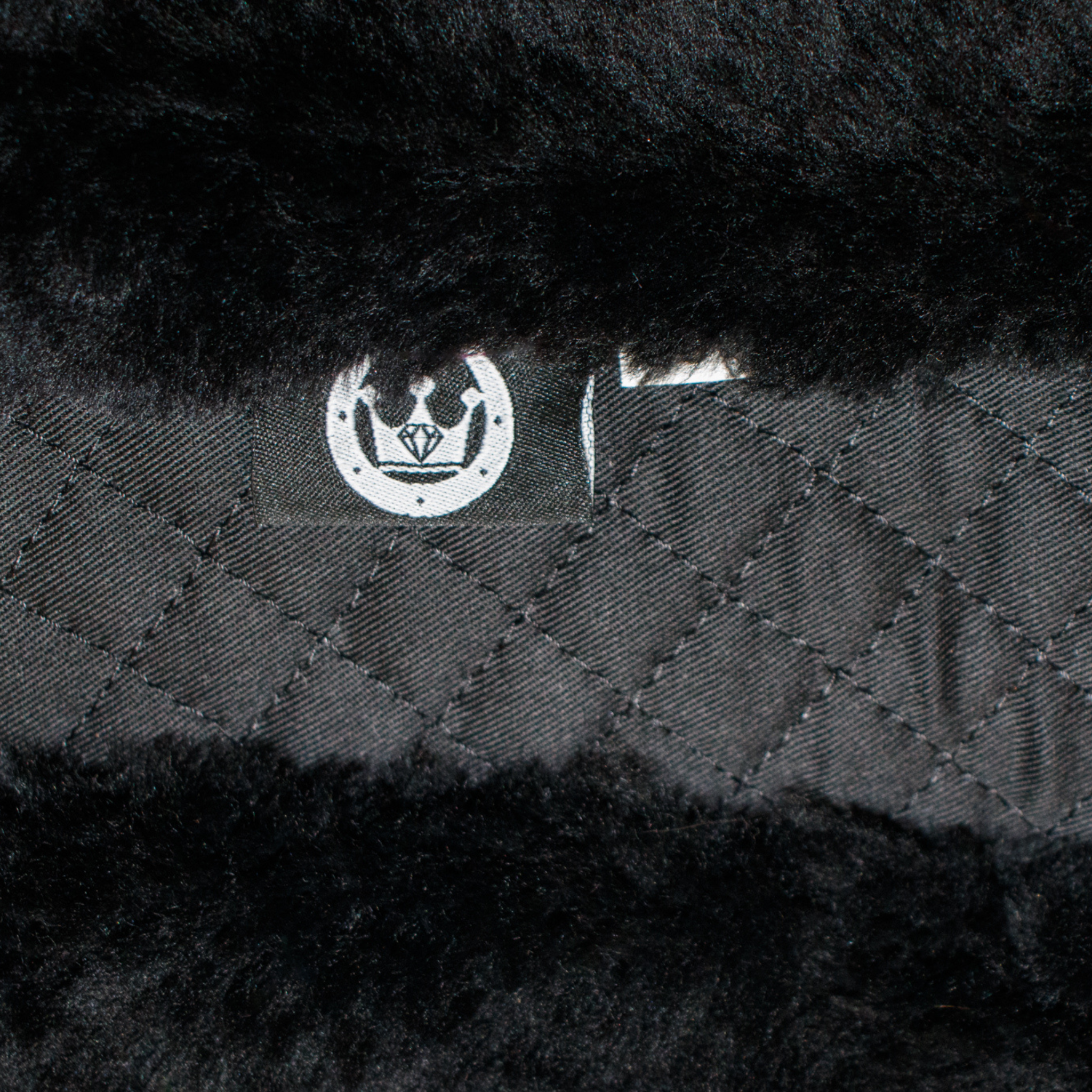 A close up photo of a black short girth with black sheepskin lining with Leveza logo tag.