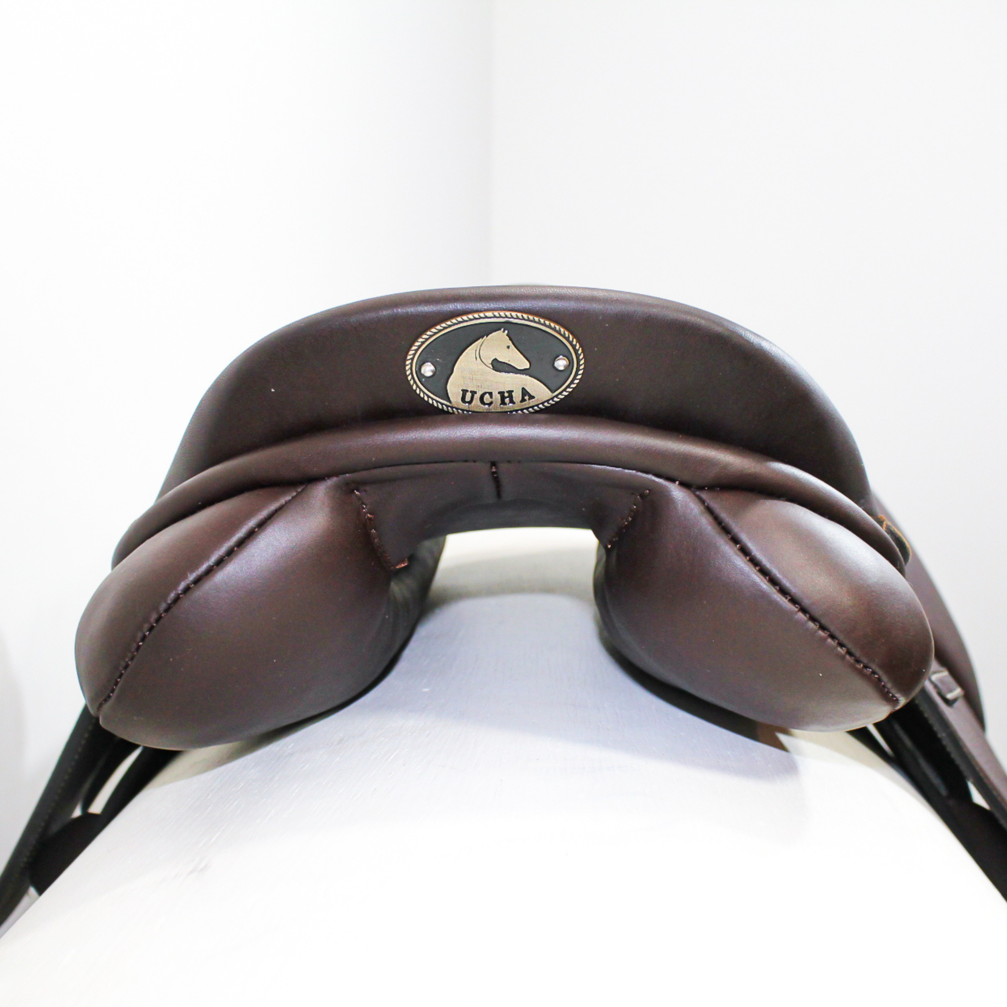 Ucha Joven kids jump saddle; rear view of cantle/rear panel area. Ucha logo plate fastened to cantle.