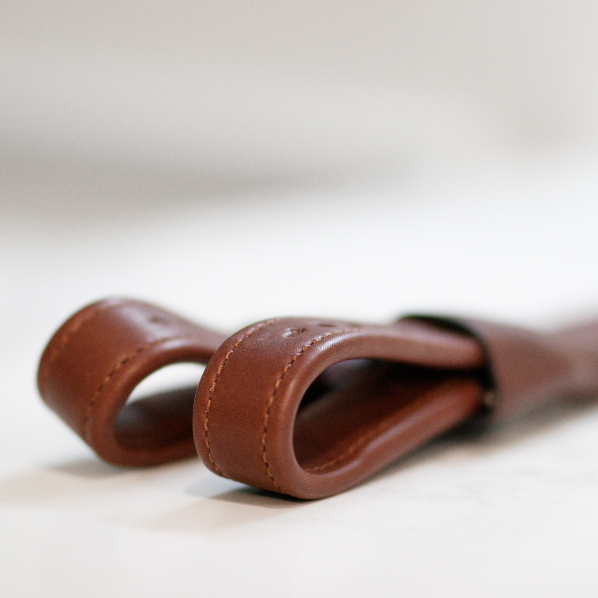 Close up photo of the bottom loop end of a pair of brown Amerigo mono stirrup leathers against a white background
