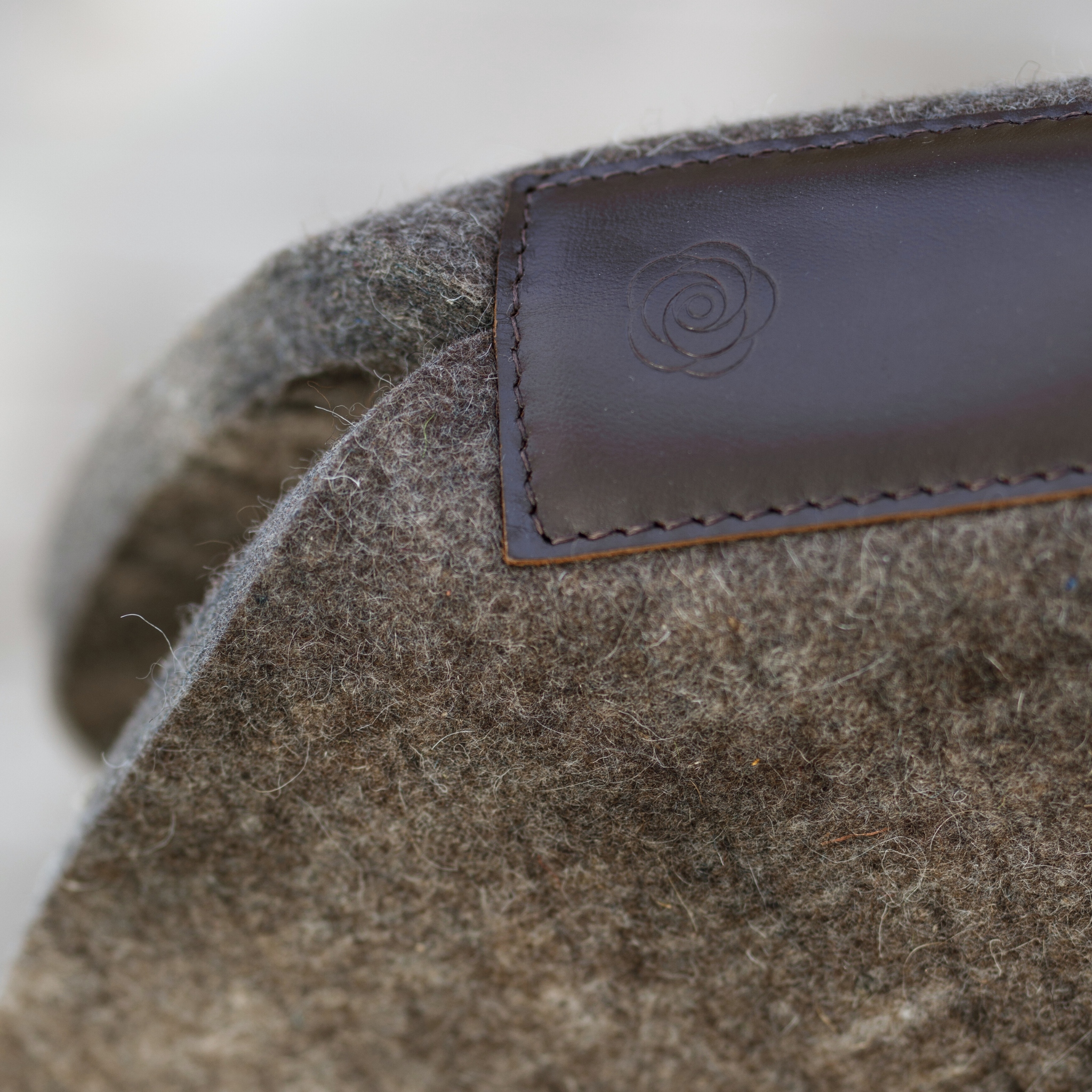 Close-up of a natural felt half pad with leather wear strip, wither-free design, and peony logo stamped into leather wear strip. 