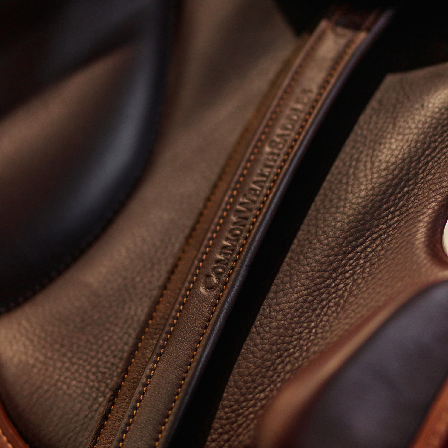 Close-up of a brown Yoho stirrup leather with caramel stitching against a saddle