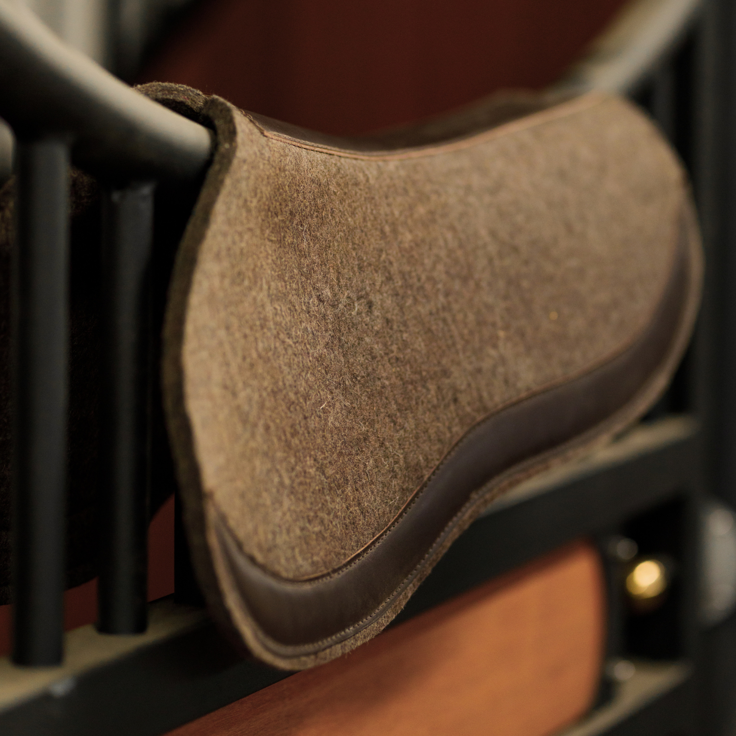 Grey/brown felt half pad with leather trim draped over a stall door