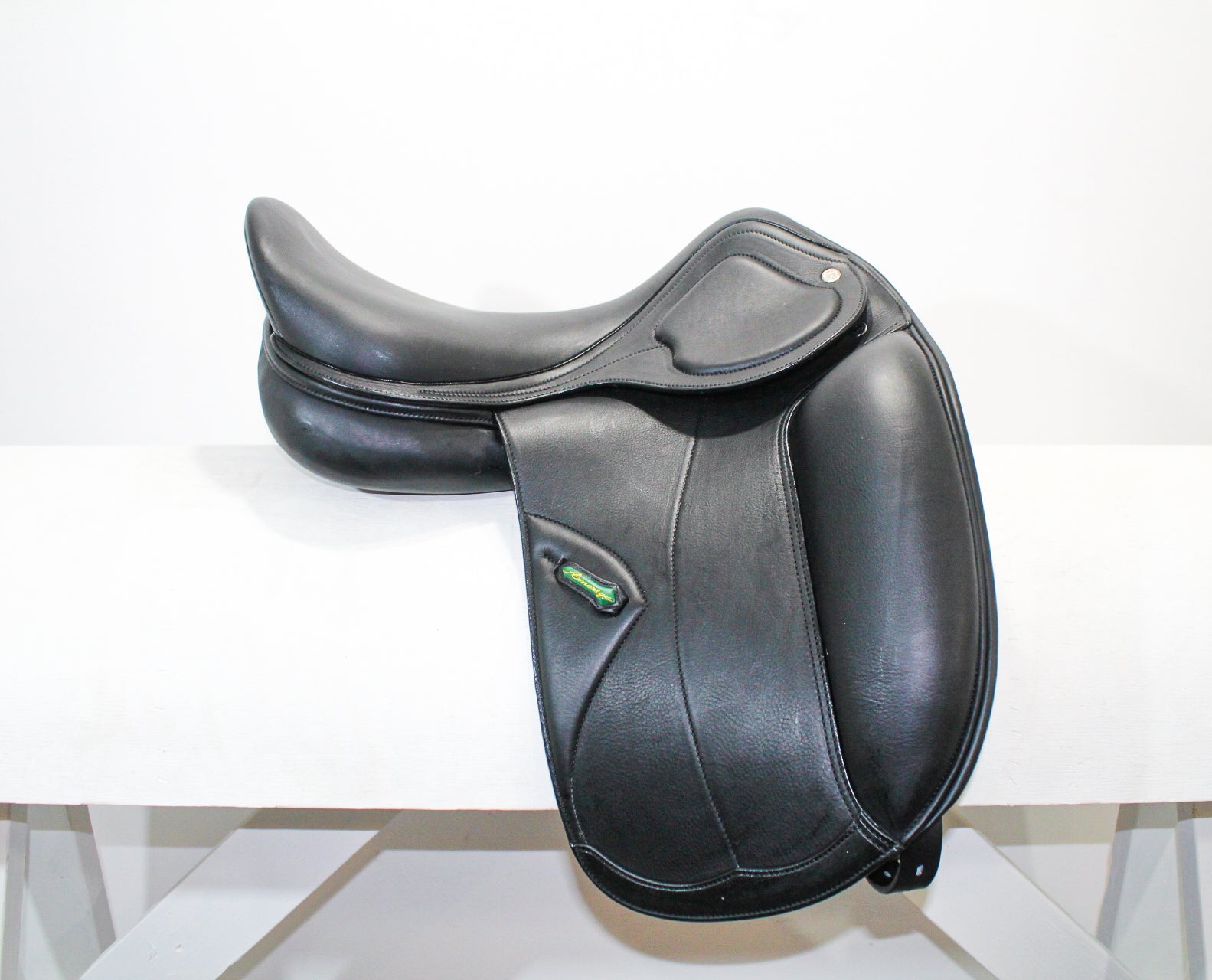 Right side profile view of an Amerigo Pasubio dressage saddle in black calf leather, with a green and yellow Amerigo logo loop. 