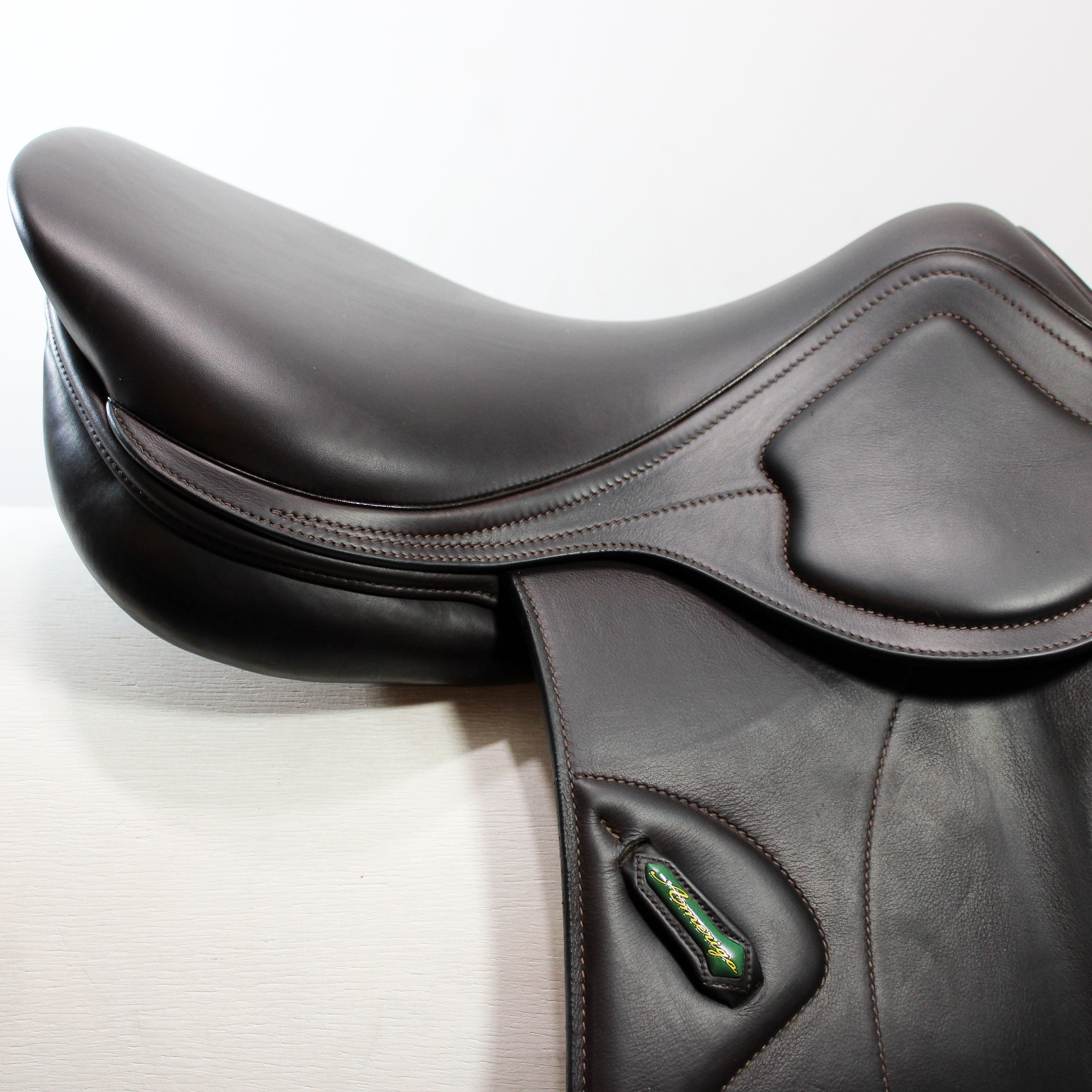 Close up right side profile view of an Amerigo DJ dual flap jump saddle in dark brown calf leather, with focus on the cantle and flap area of the saddle.