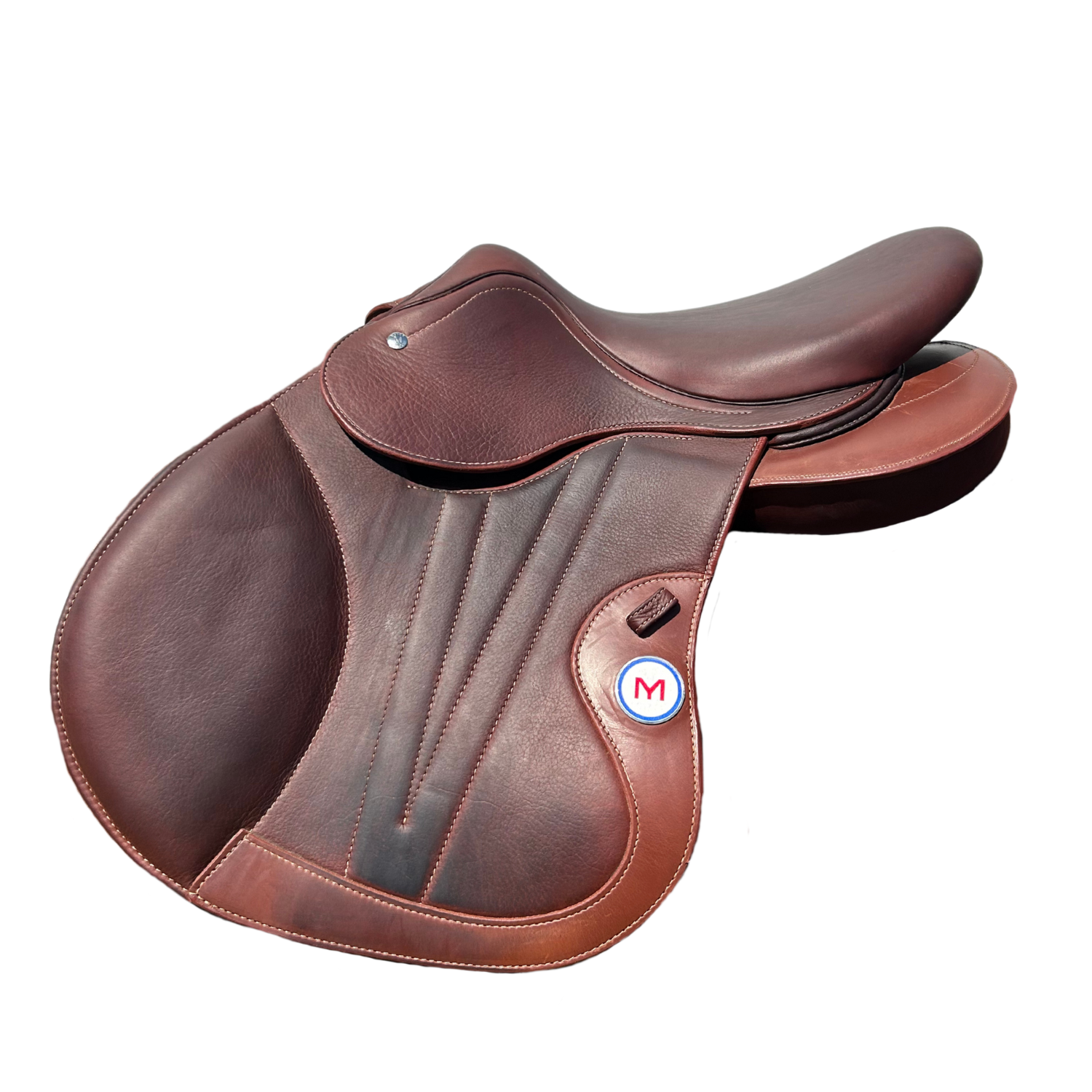 Side view of a brown calfskin leather Meyer Metamorphose jump saddle with a circular white badge featuring a red letter 'M' and a small French tricolor detail. The saddle has detached rear panels and a cutback pommel.
