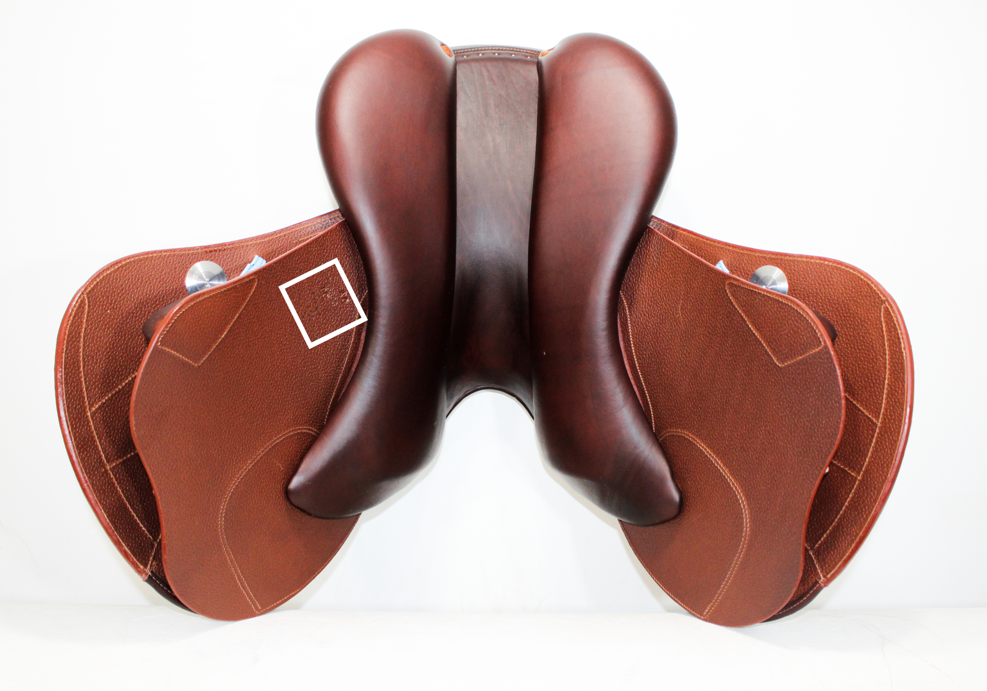 Underside view of a brown leather Meyer Act 2 jump saddle with a white box around the stamp to highlight its location. 