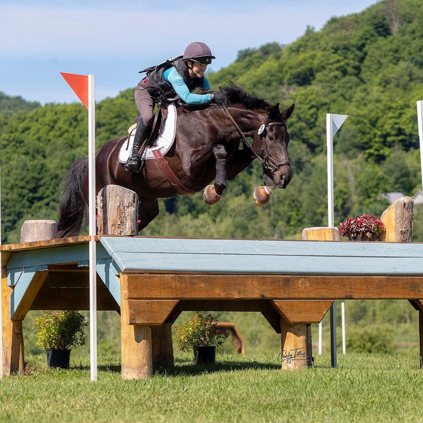 Sam Pritchard and her horse jumping a tabletop obstacle at a cross country competition.