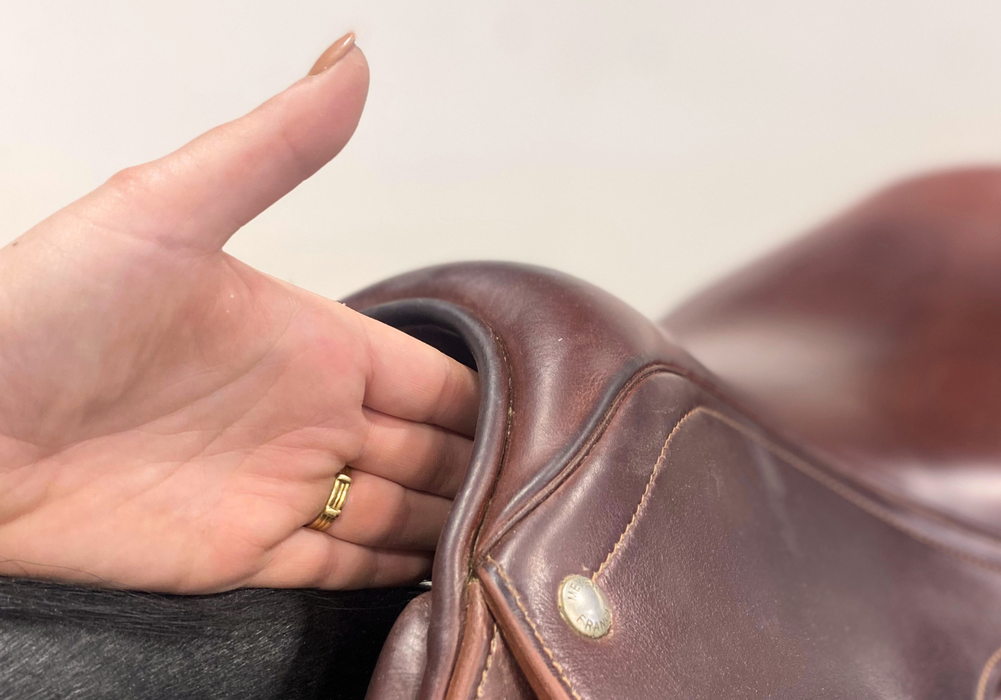 Close-up of a hand stacked under the pommel of a saddle to demostrate acceptable wither clearance.