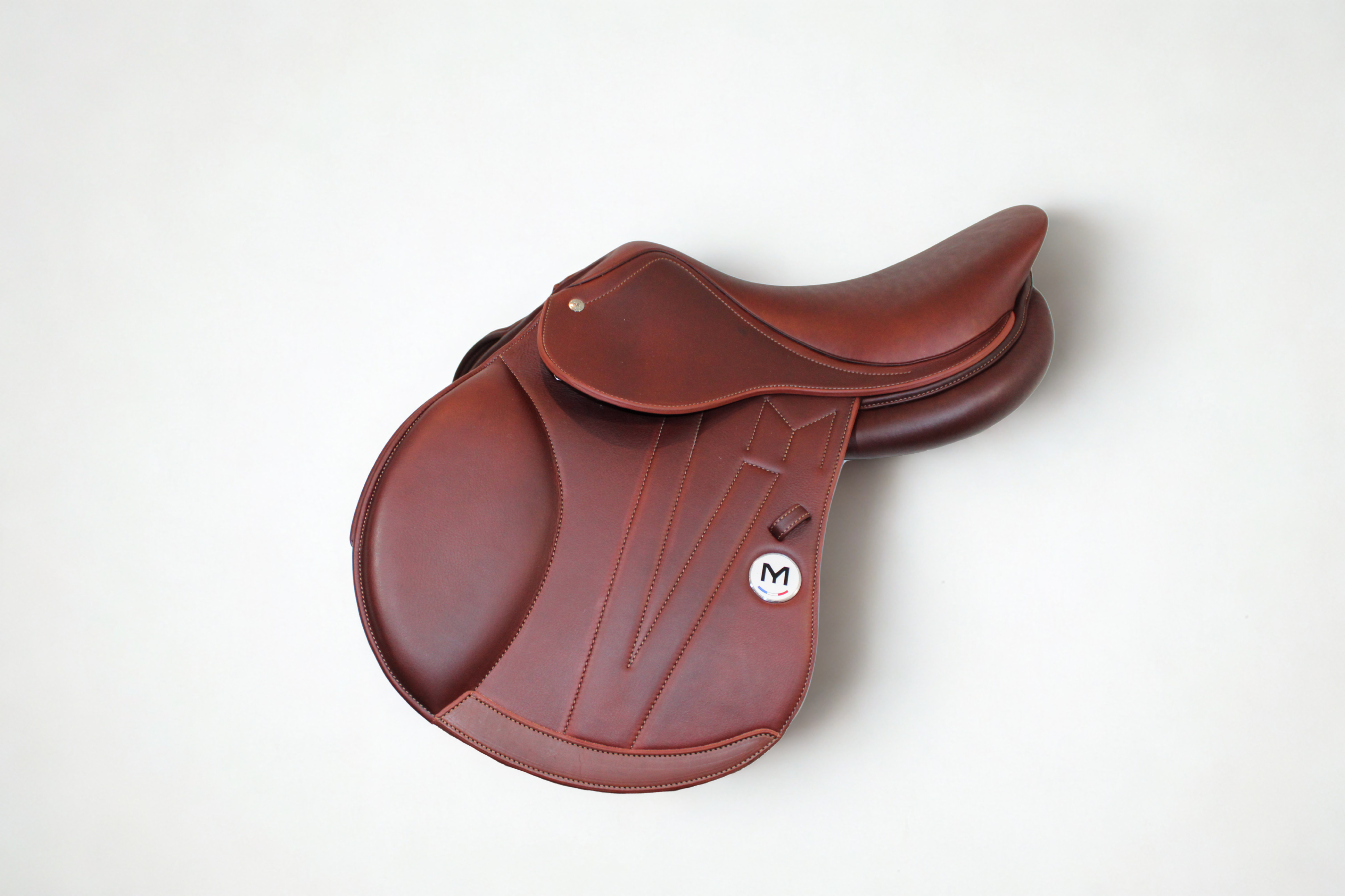 Left side profile view of a Meyer Act 1 jump saddle in brown calf leather, with a white Meyer logo, decorative stitching, and lower flap reinforcement.